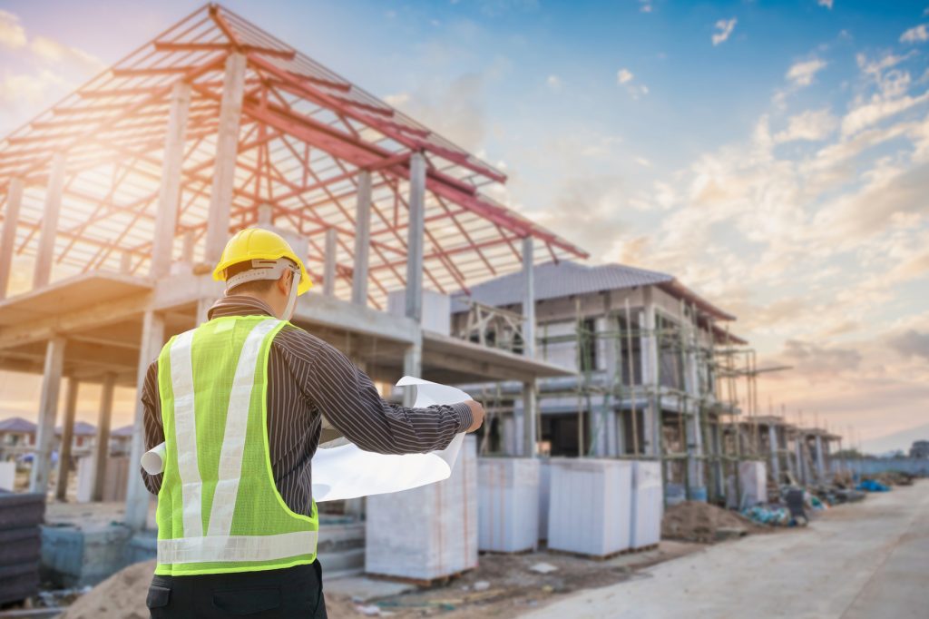 Professional engineer architect worker with protective helmet and blueprints paper at house building construction site background (Professional engineer architect worker with protective helmet and blueprints paper at house building construction site b